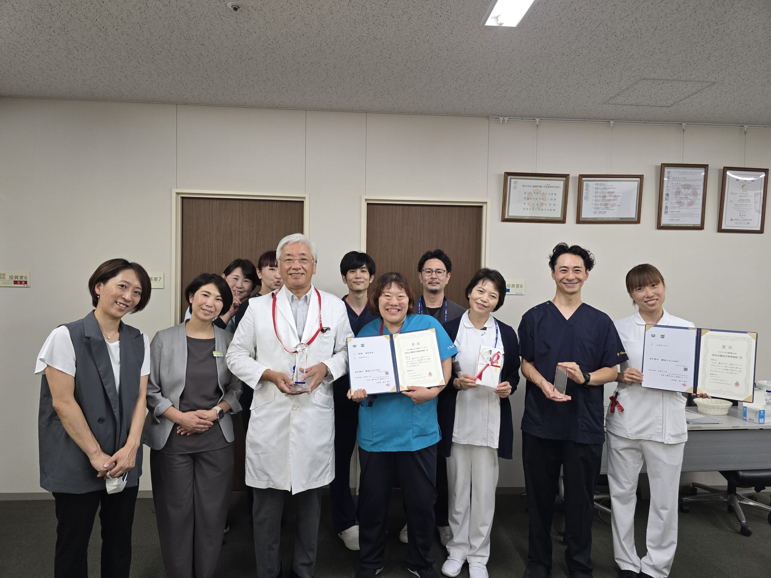 看護部SNSチームメンバーと三角隆彦院長がトロフィーや賞状を持っている写真