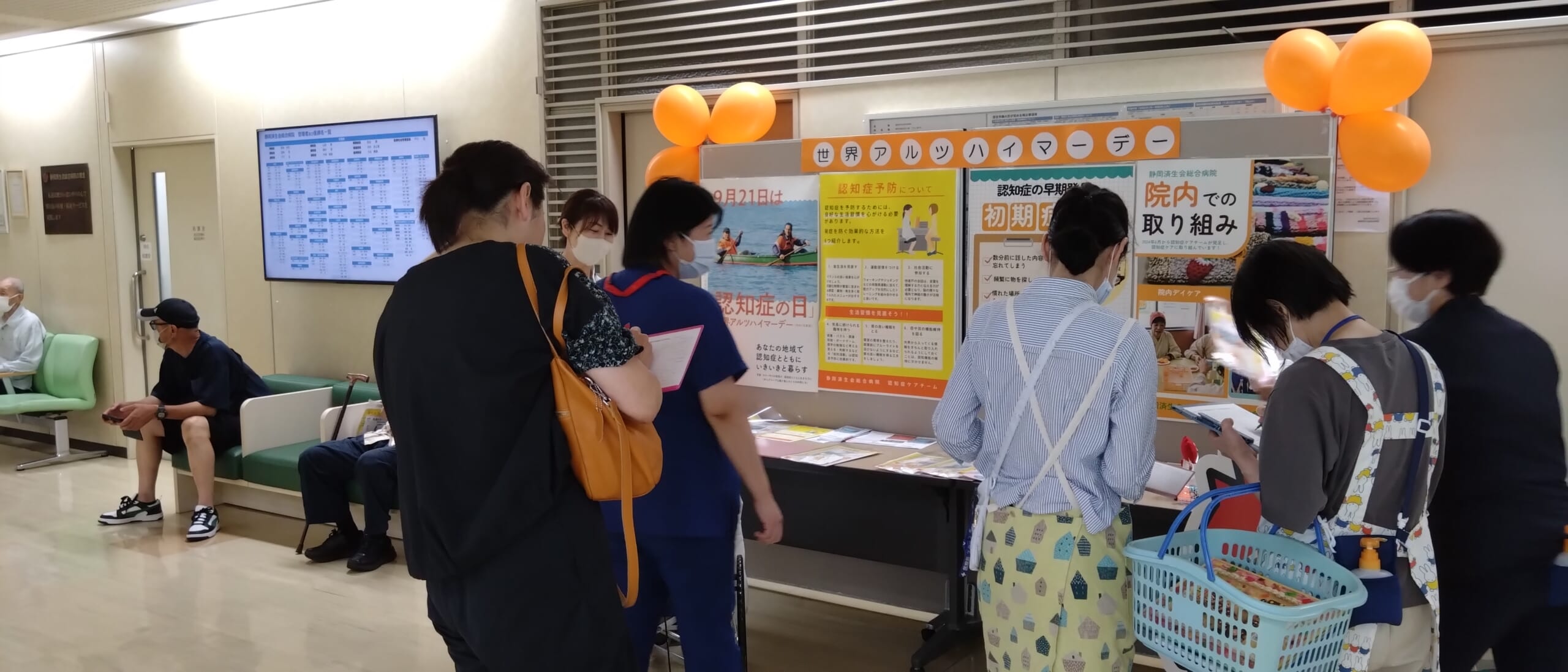 来院者が認知症に係るポスター展示を読んだり、リーフレットを職員から受け取っている写真