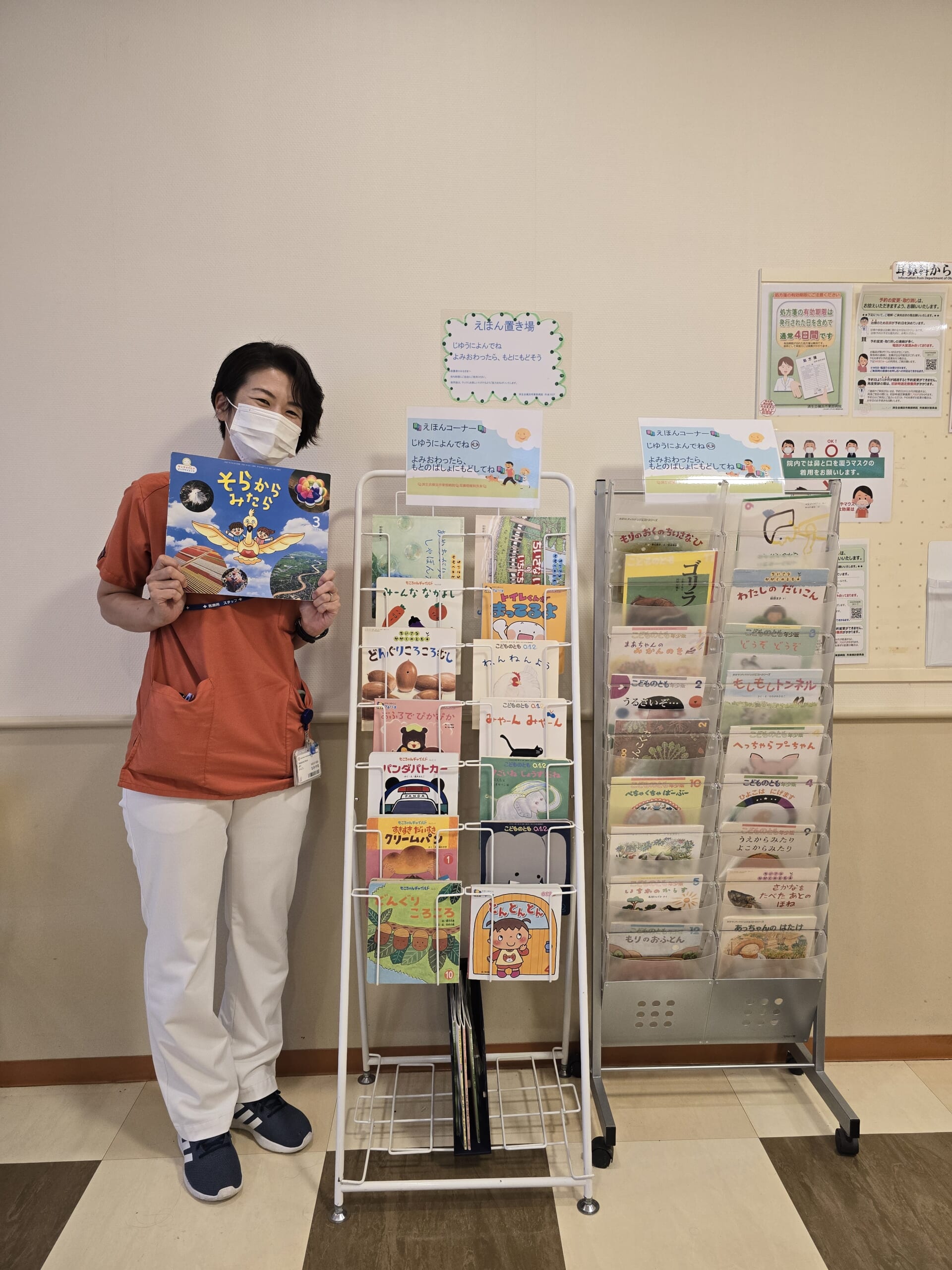 中山さんがラックの近くで絵本を持っている写真