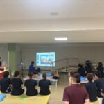 村田浩人副院長がスライド資料を用いて、患者急変時対応を説明し、参加者が聞いている写真