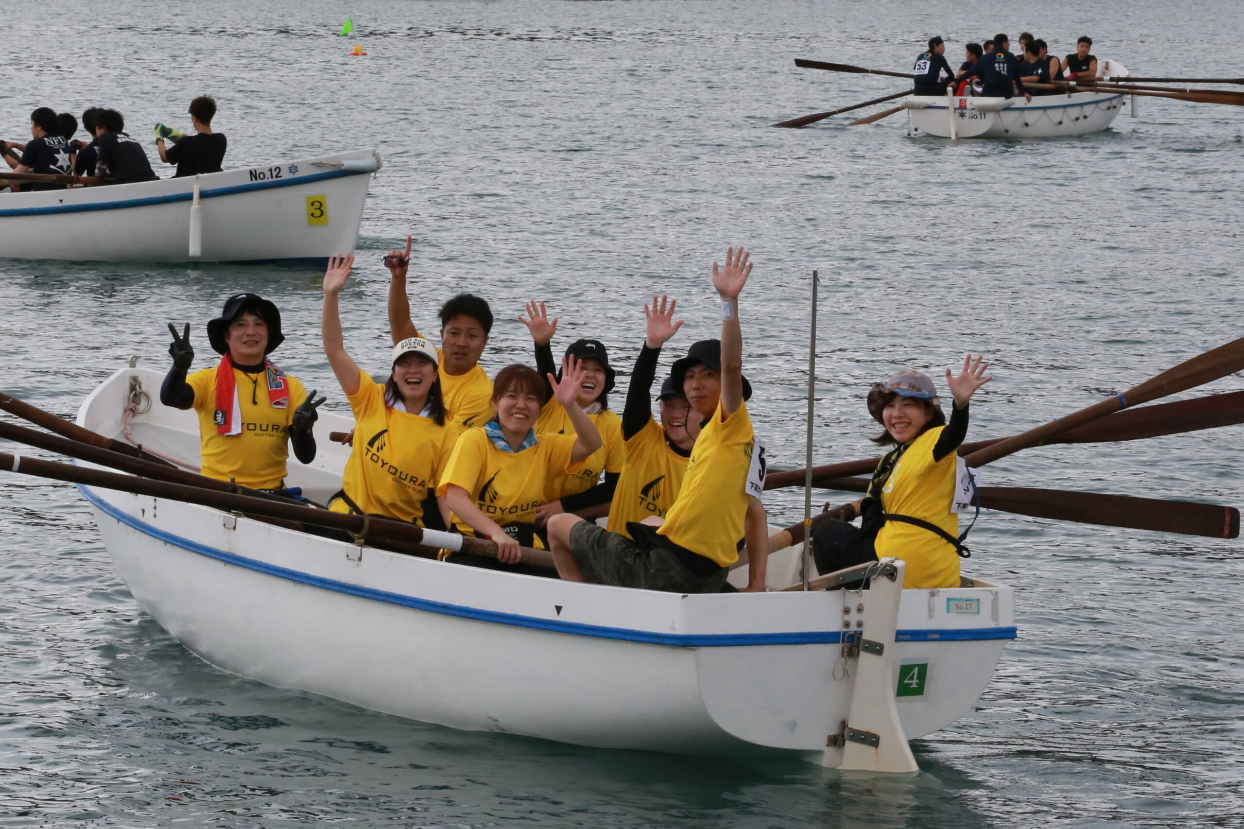 船の上で、参加したメンバーが笑顔でピースをしている写真