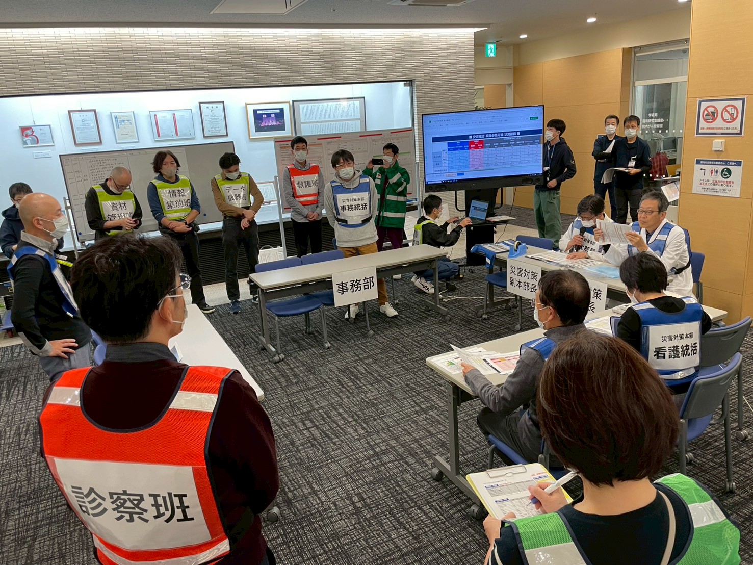 職員たちが災害を想定し、情報収集や安否確認・搬送先調整等を話し合っている写真