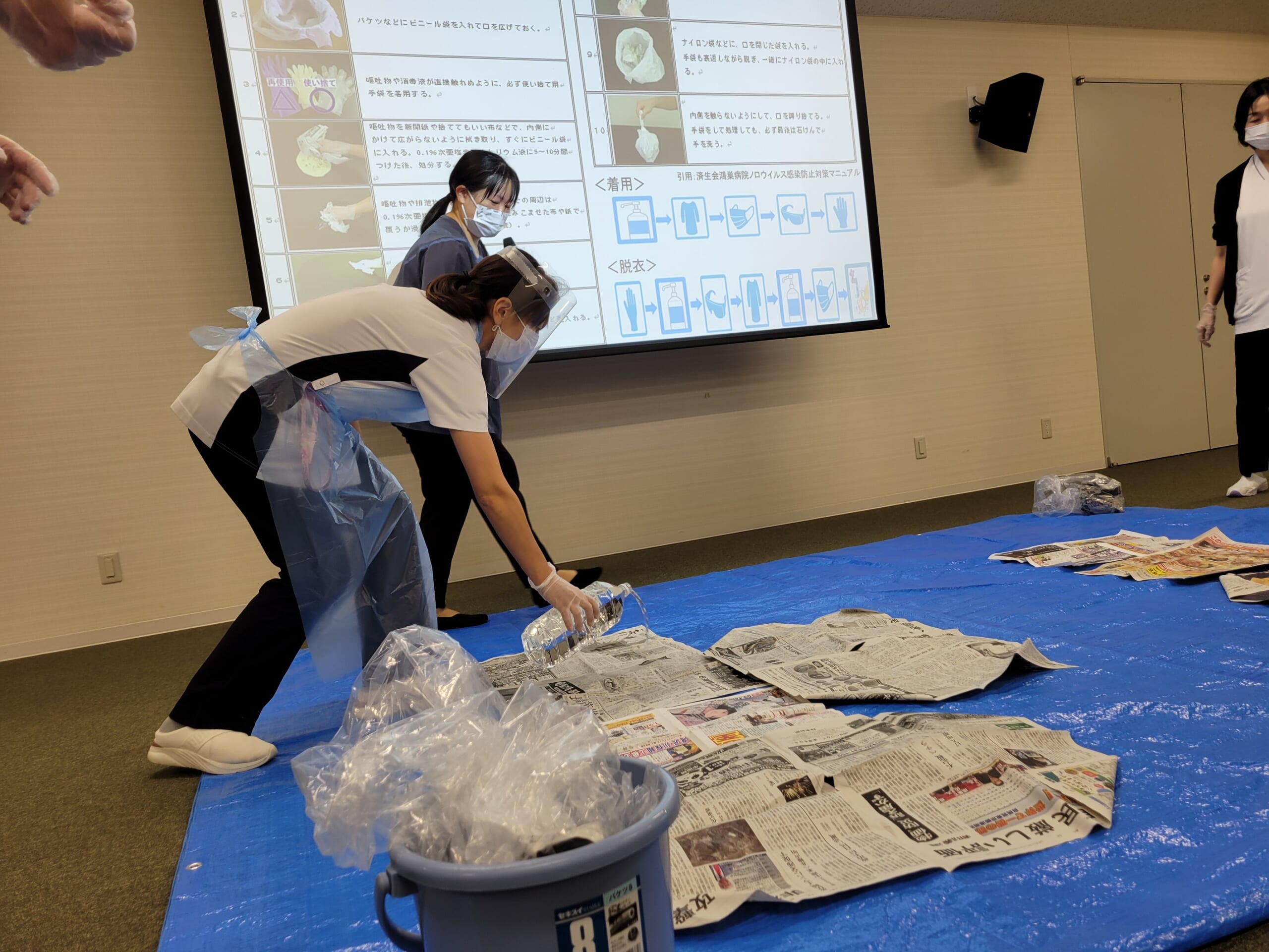 参加者が吐しゃ物の処理方法を演習している写真