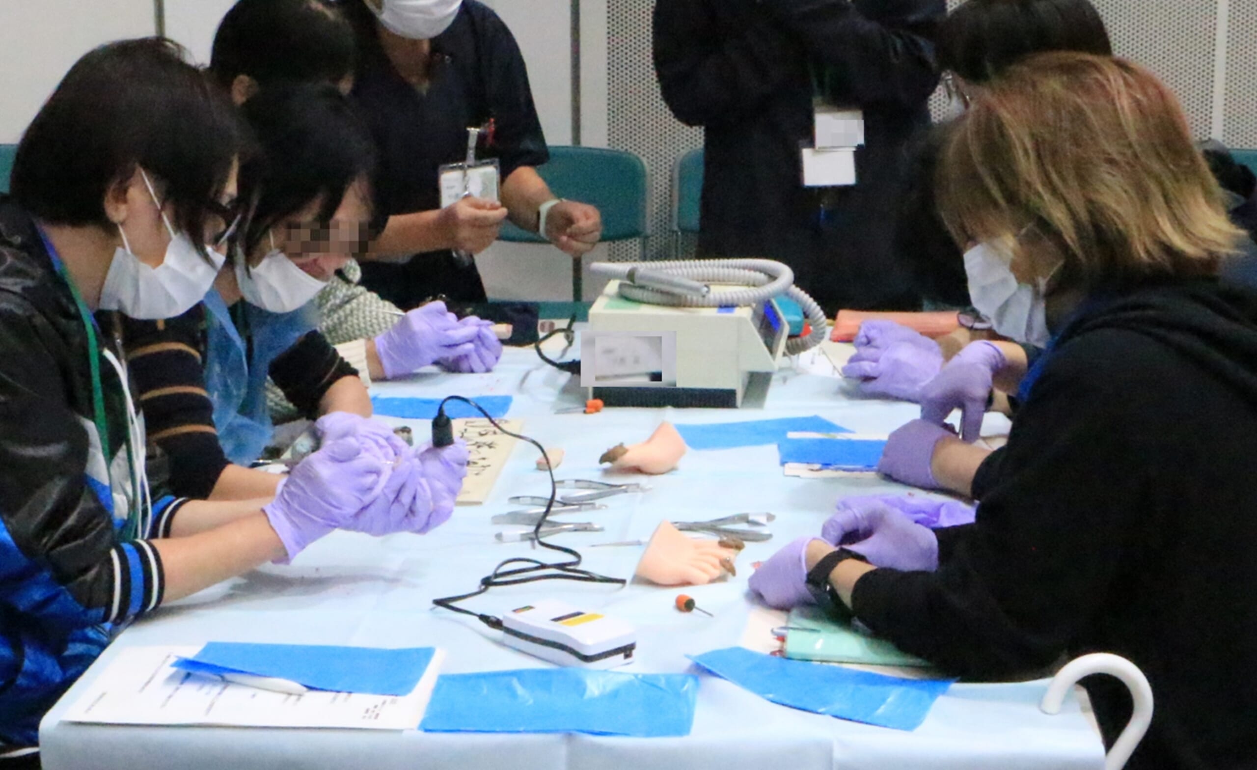 参加者がリアルな足モデルや、爪ゾンデ・グラインダーなどの手作り教材を用いた実技演習をしている写真