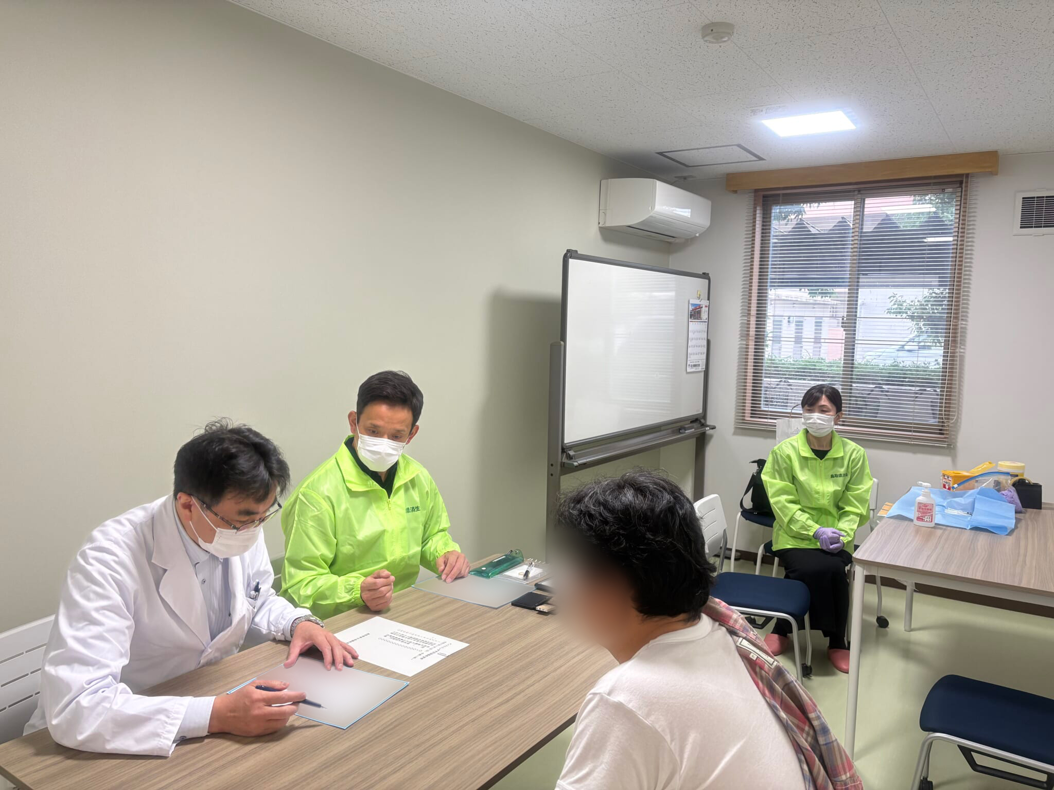 岡野淳一センター長が入寮者にインフルエンザワクチンについて説明している写真