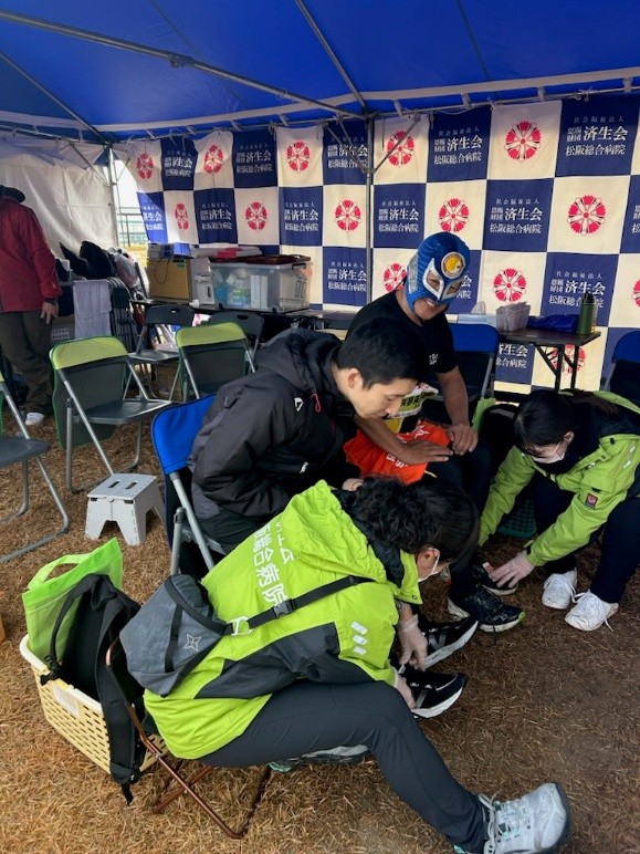 〈三重〉松阪総合病院の職員が参加者に正しい靴の履き方を教えている写真