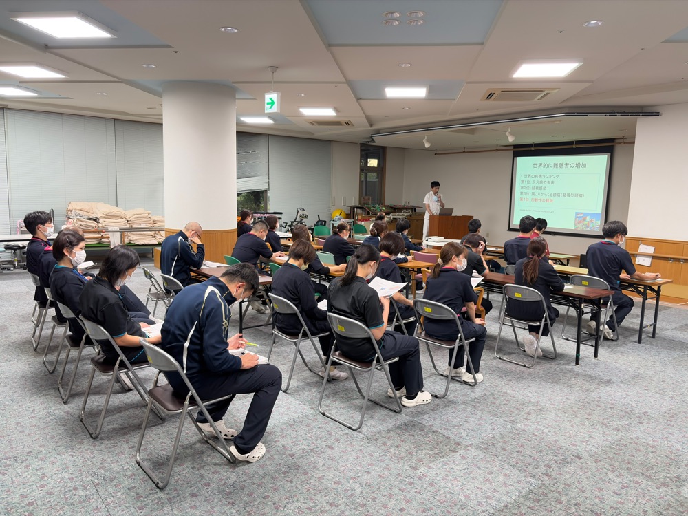 福井県済生会病院耳鼻科・清水良憲医師が参加者である介護老人保健施設ケアホーム・さいせいの職員に難聴に係る講義をしている写真