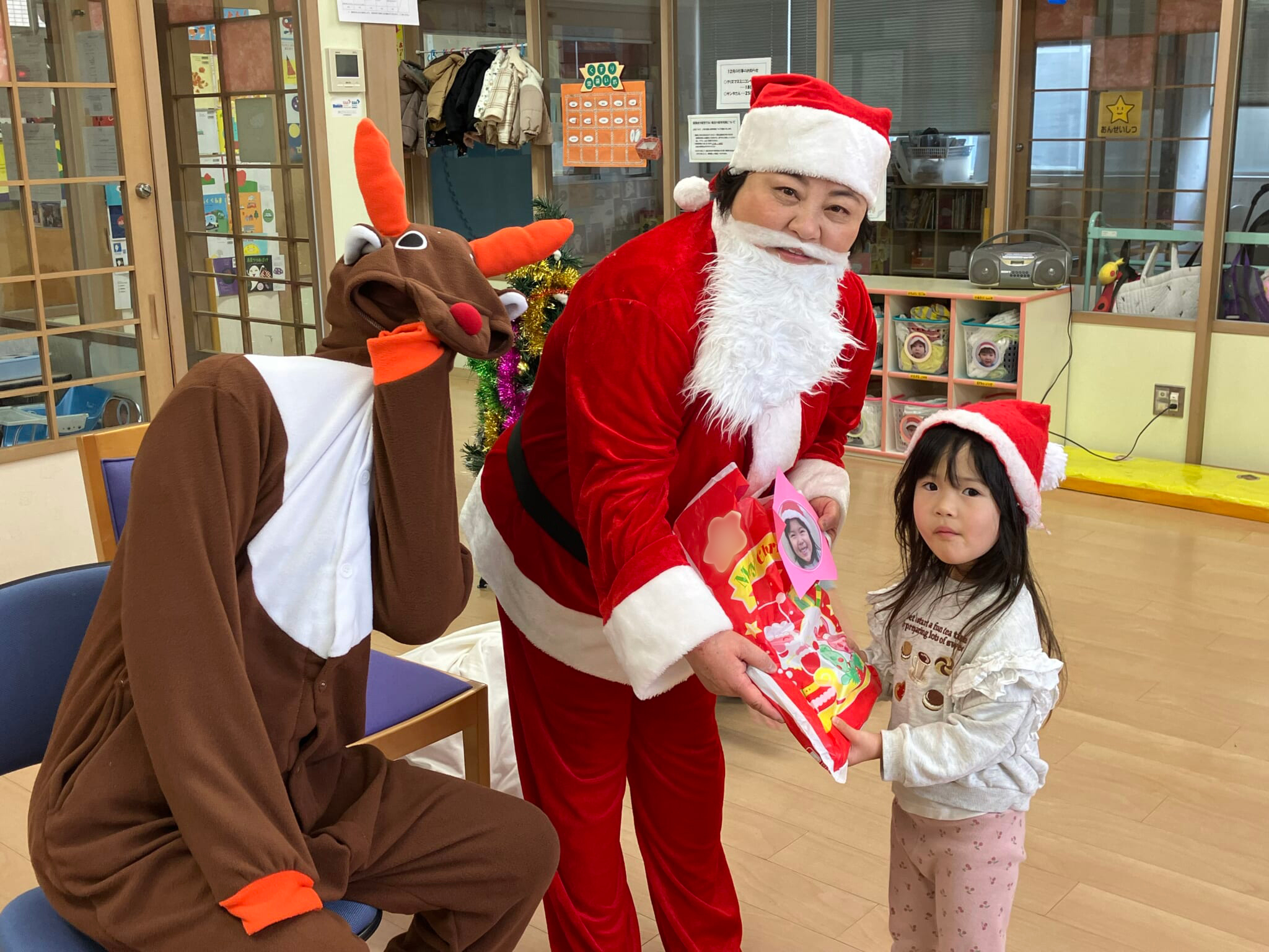 トナカイに扮した大田麻紀看護部長が子どもにプレゼントを手渡している写真