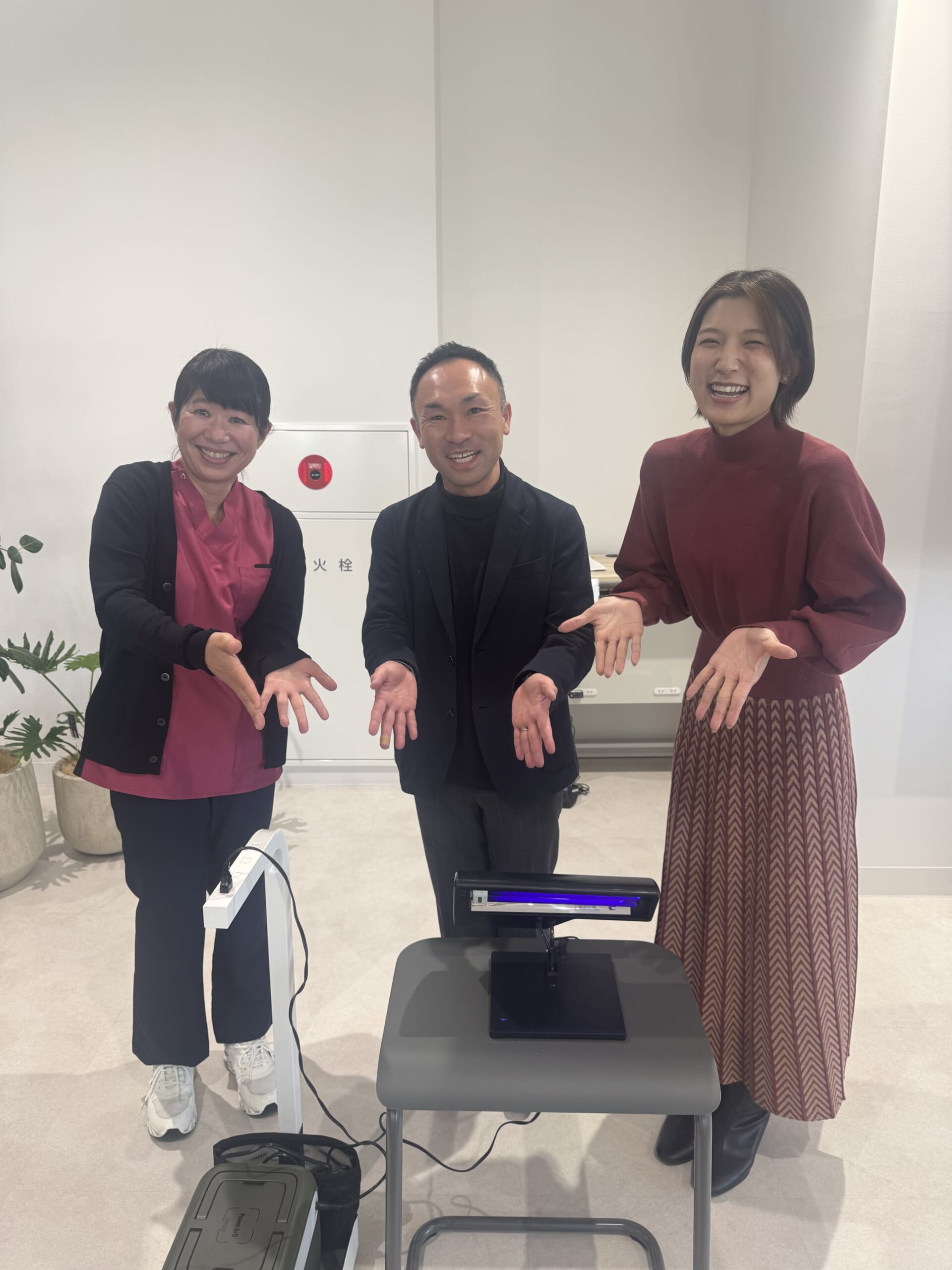 蛍光塗料を使った手洗い体験装置と感染管理認定看護師・櫻井佐智子師長含む3人の登壇者の写真