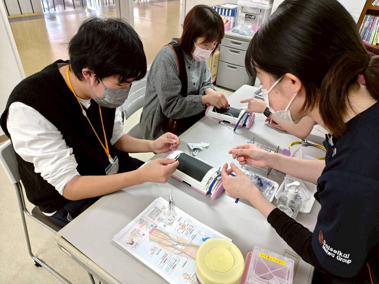 参加者が疑似腕を用いた採血体験をしている写真