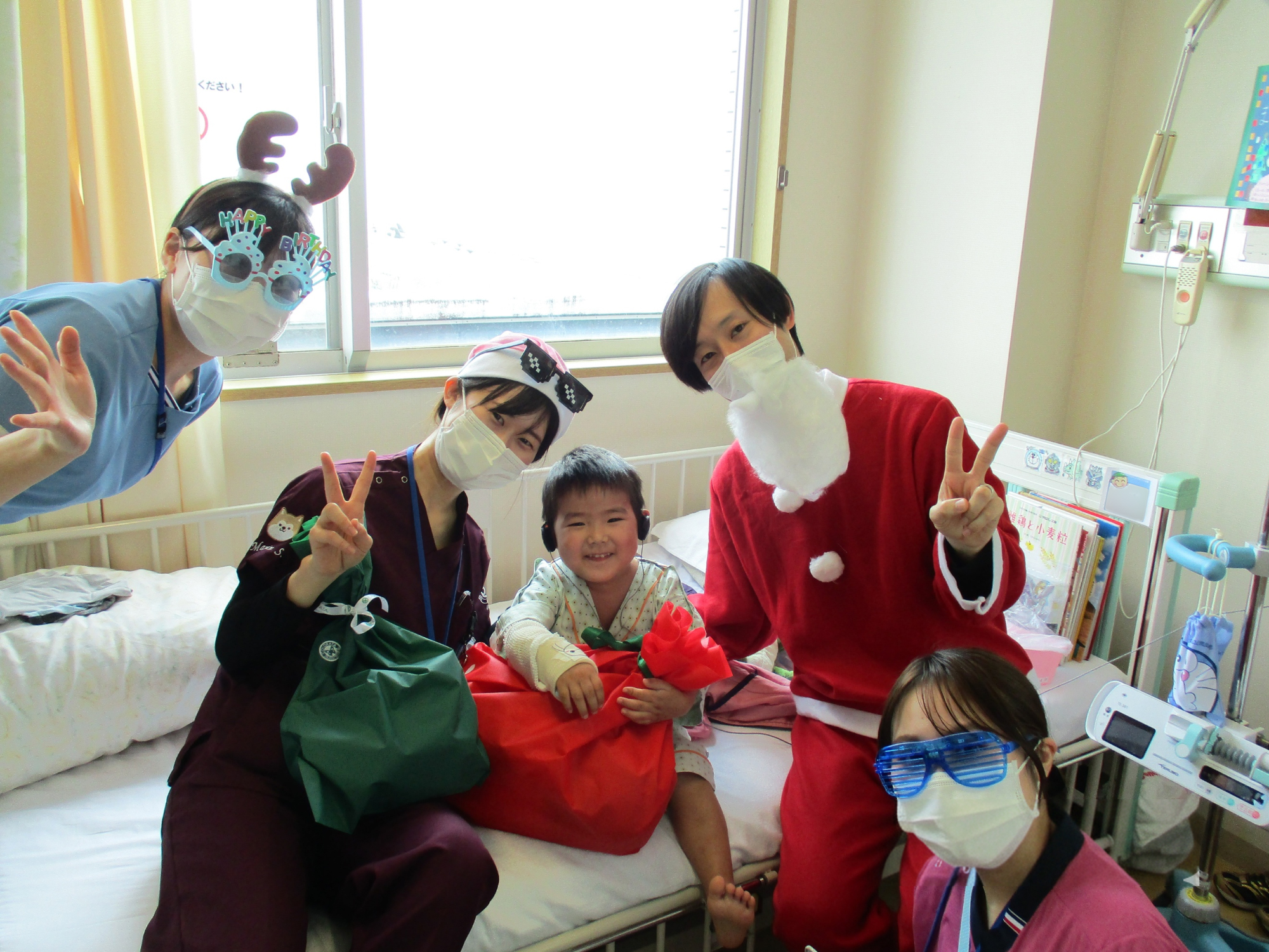 サンタクロースとトナカイに扮した職員3人と小児科病棟の子どもとの記念写真