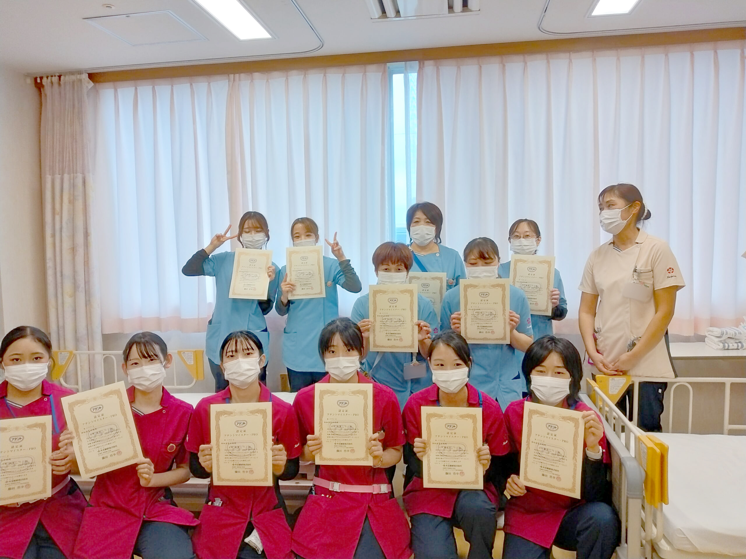 全課程を終え試験に合格した30人の看護師が大王製紙が認定する「アテントマイスター・プロ」という排泄介助のスペシャリストの認定証とバッジをもっている写真