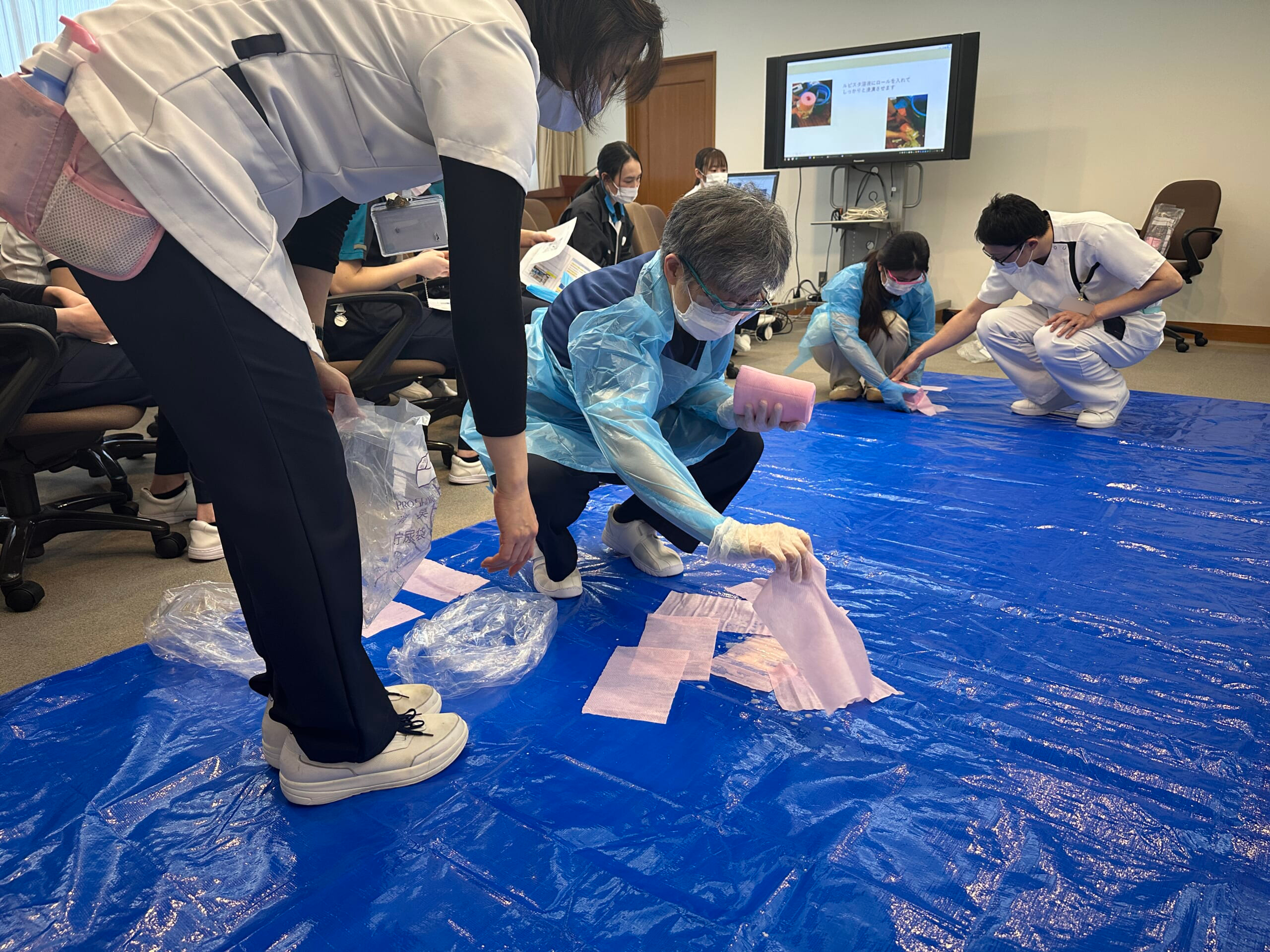 防護具の着用し、拭き取り作業の模擬訓練をしている写真