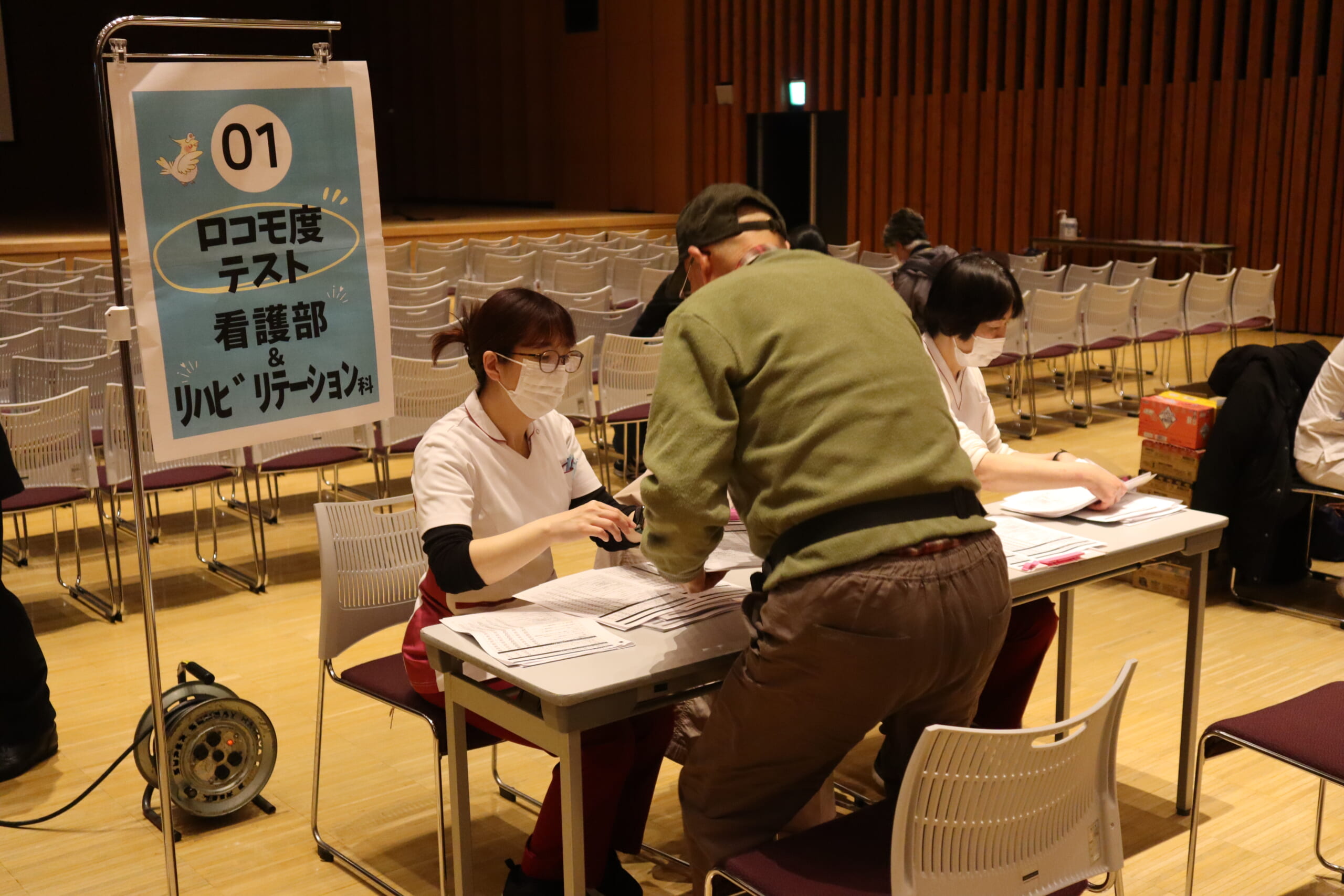 看護師と理学療法士が参加者にロコモ度テストを行っている写真