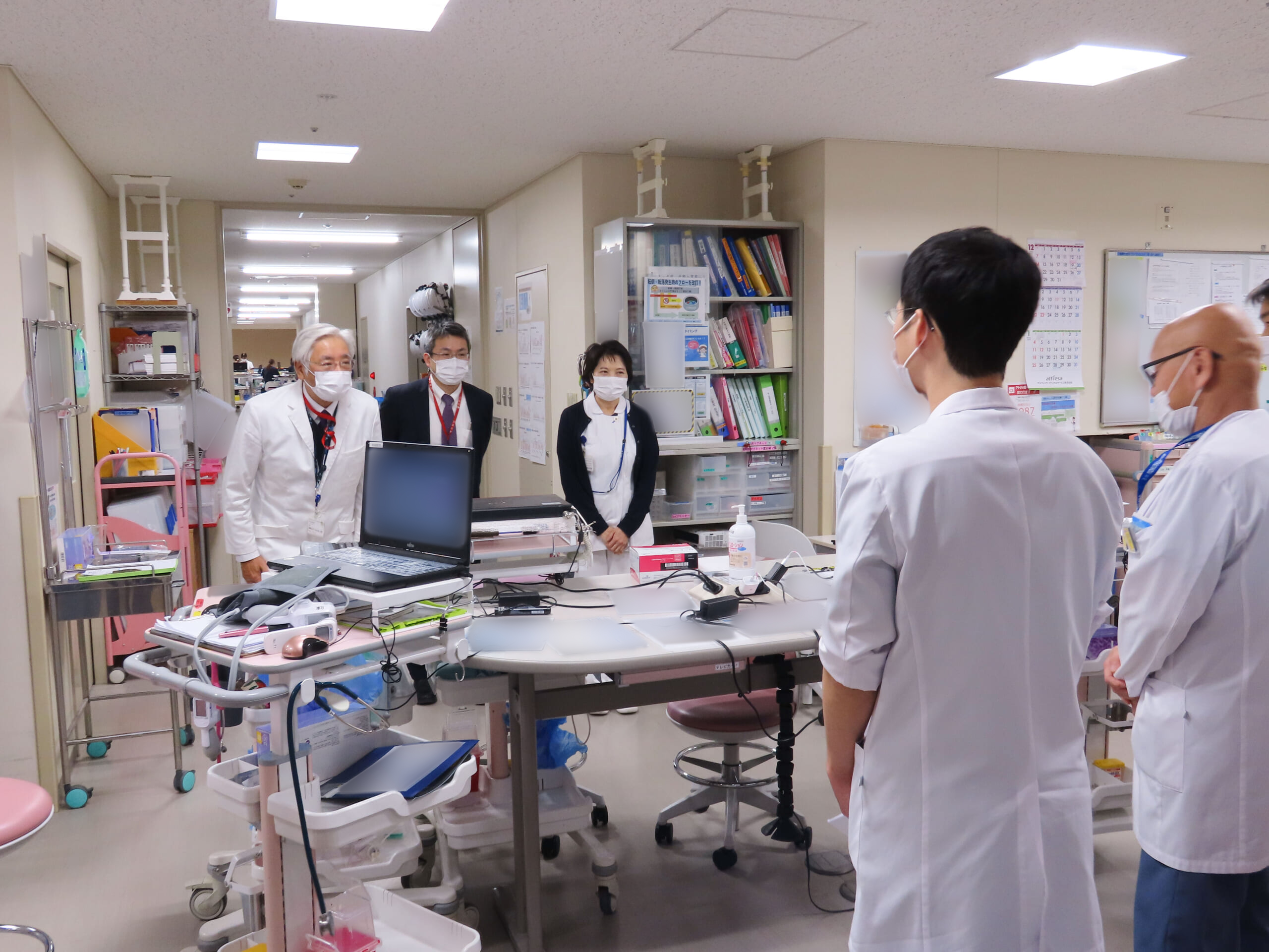 三角隆彦院長、渡邊輝子看護部長、髙杉知史事務部長代行が職員に声をかけている写真