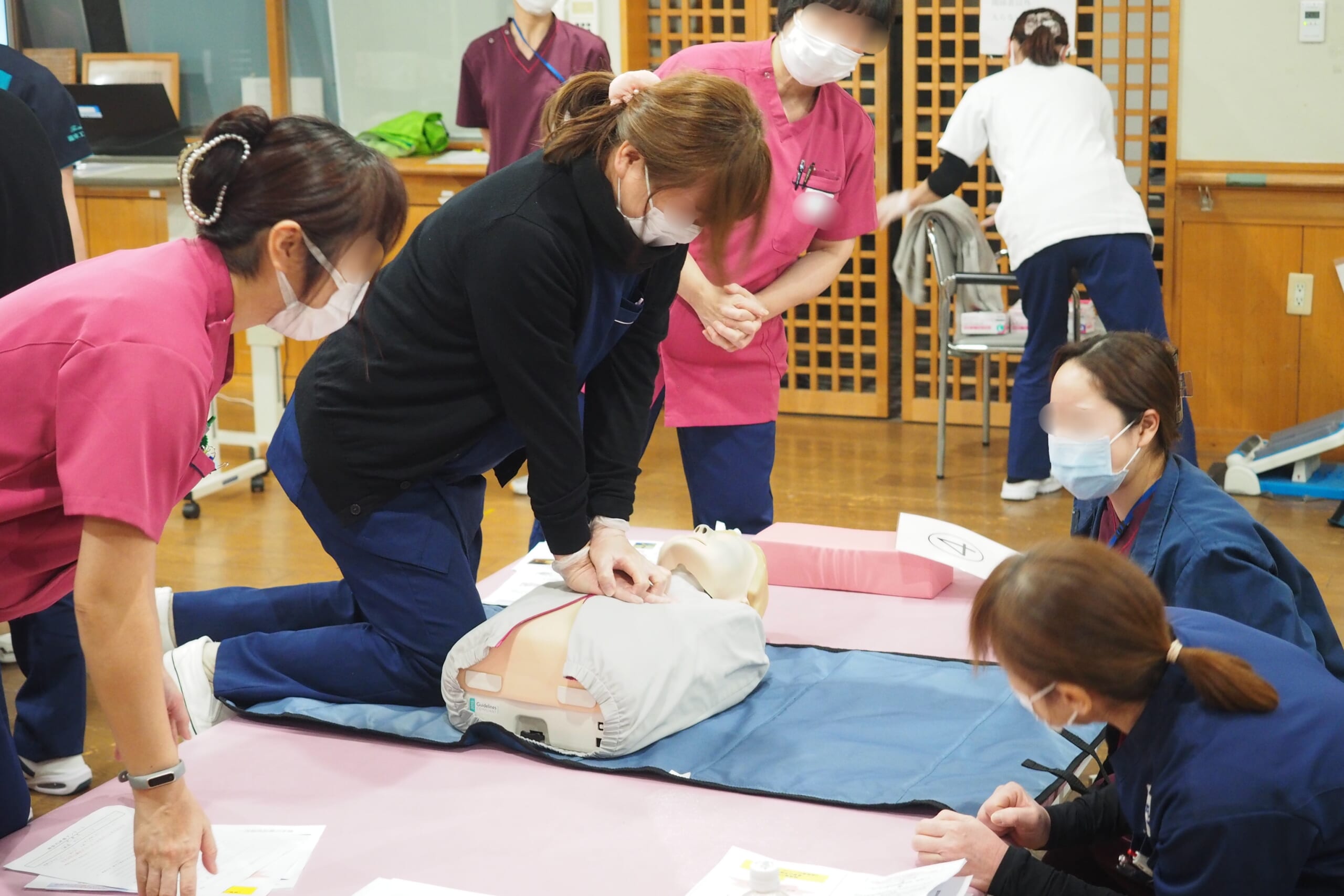 富田林市老健けあぱるの職員が人形を用いて心臓マッサージを練習している写真